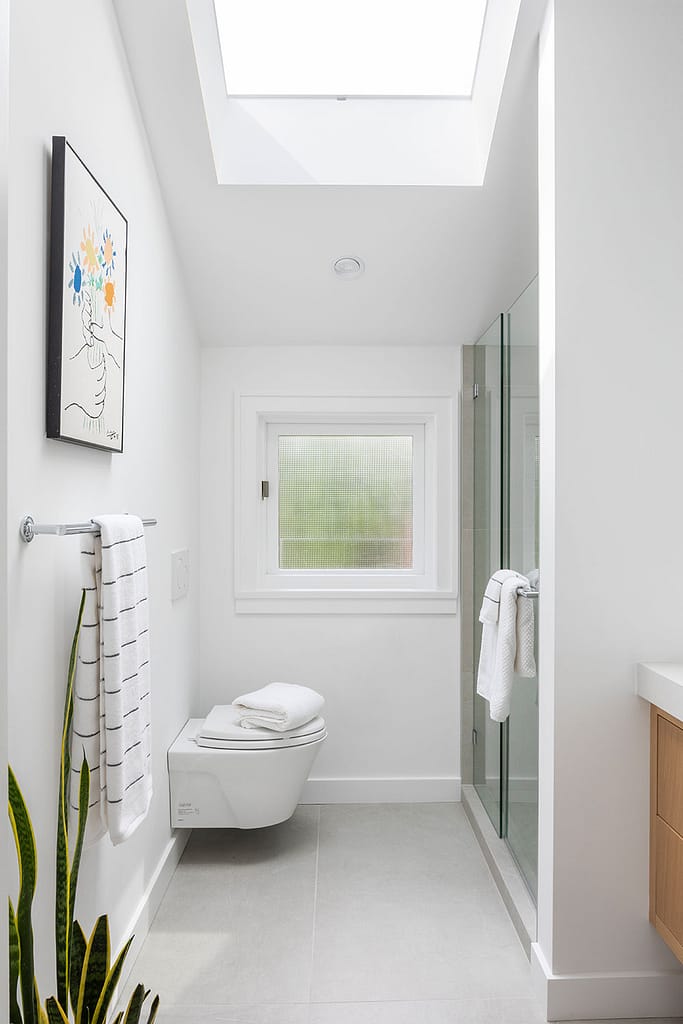 Renovated upstairs bathroom with angled roof and skylight and a floating modern toilet and large shower